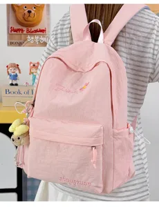 Detailed view of the pink student backpack with embroidered flower pattern and cute bear pendant.