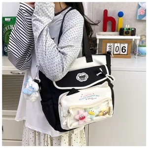 Close-up detail of the black and white canvas shoulder tote bag with transparent pocket and charms.
