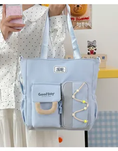 Vista detallada del bolso tote de lona azul claro con múltiples bolsillos y correa.