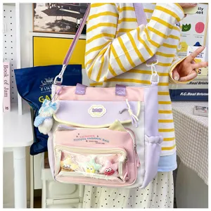 Cute canvas shoulder bag with large capacity, transparent front pocket, and pastel design for students.