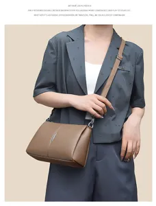 Detail shot of a stylish brown leather crossbody bag worn by a model in a professional blazer.