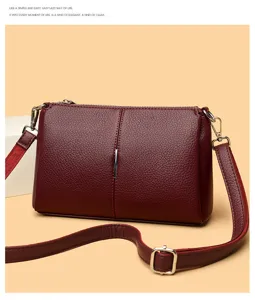 Detail shot of wine red leather crossbody bag, featuring metallic vertical clasp and zip.