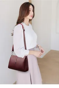 Detail shot of wine red leather shoulder bag worn by model, showcasing strap and texture.
