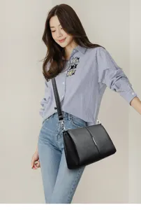 Detailed view of the elegant black leather crossbody bag worn by model, showing texture.