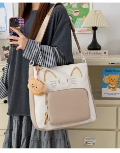 Canvas cat shoulder tote bag detail with cute bear pendant and contrasting color design.