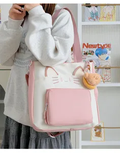 Close-up detail of the cute cat-themed pink and white tote bag with front pocket and plush charm.