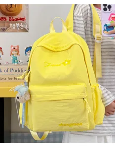 Close-up detail of the vibrant yellow canvas backpack showing embroidery and side pocket.