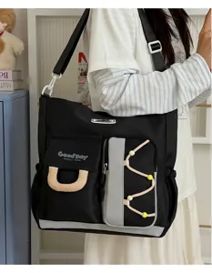 Vista detallada del gran bolso bandolera de lona negra con diseño de múltiples bolsillos diarios.