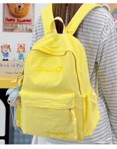 Detailed view of yellow casual backpack with cute embroidered flower and front pocket design.