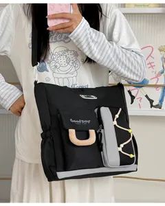 Primer plano del bolso cruzado negro de múltiples bolsillos con detalles frontales.