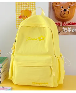 Detail view of cute yellow student backpack with sweet embroidery flower and front pocket design.