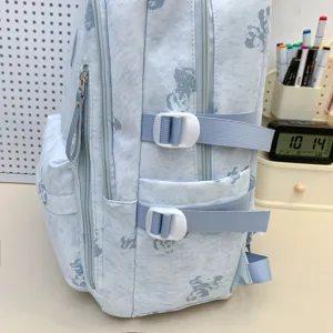 Light blue canvas school backpack with cartoon print, multi-compartment design and side straps.