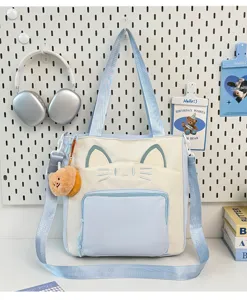 Detail view of a cute cat canvas tote bag with color block design, crossbody strap and bear.