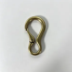 Primer plano del mosquetón de resorte de bronce, mostrando curva metálica suave y acabado mate.