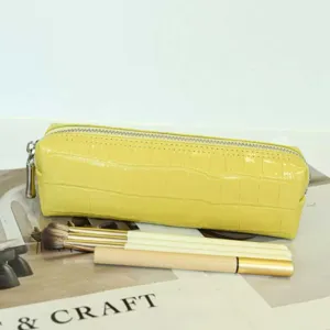 Yellow crocodile pattern leather makeup pouch detail shot, compact storage bag with zipper.
