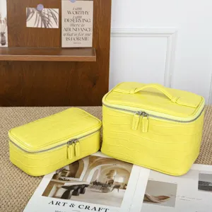 Detalle del neceser de maquillaje amarillo con estampado de cocodrilo y cremallera metálica.