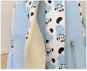 Cute cartoon puppy print backpack detail, light blue student school bag material close-up.