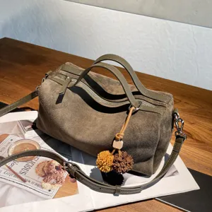 Vue détaillée d'un sac Boston vintage en daim vert foncé avec bandoulière et charm.