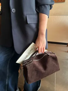 Vue détaillée d'un sac Boston vintage en daim marron, soulignant la texture du cuir souple.