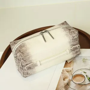 Detail shot of a luxury crocodile pattern cosmetic bag with double zippers for travel.