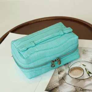 Turquoise crocodile pattern cosmetic bag close-up highlighting texture, double zipper and handle.