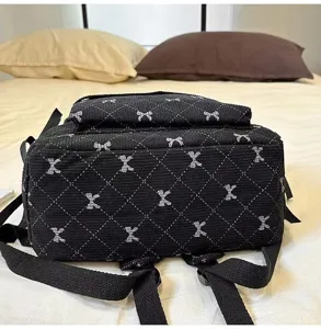 Close-up detail of the black quilted backpack featuring a cute bow pattern and adjustable straps.