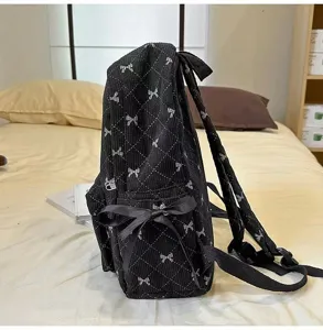 Black corduroy backpack with bow detail, detailed side view showing quilted design.