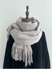 Primer plano detallado de bufanda de invierno gris claro efecto cachemir con elegantes flecos.
