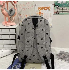 Detailed view of grey corduroy backpack featuring black bow pattern, casual student school bag.