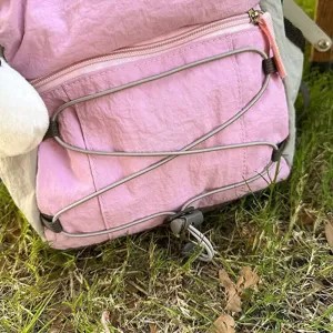 Pink mini backpack detail view with bungee cord and zipper pocket for casual outdoor travel.