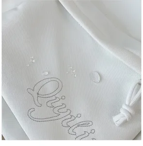 Close-up detail of white waterproof student backpack fabric with stylish cursive embroidery.