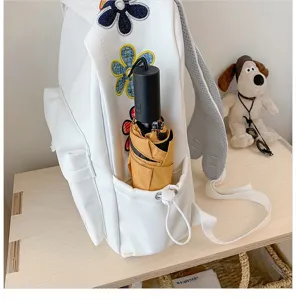 Close-up detail of white canvas student backpack with colorful embroidered flowers.