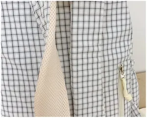 Close-up detail of casual black and white plaid backpack with mesh strap and zipper pocket.