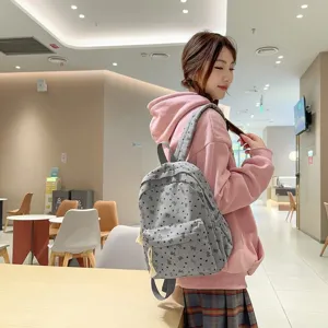 Detailed lifestyle shot showcasing the grey bow print backpack worn by a model in a modern interior setting.