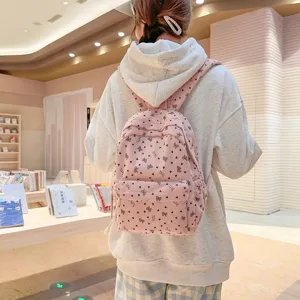 Detail view of pink corduroy bow backpack, sweet college style student bookbag in bookstore setting.
