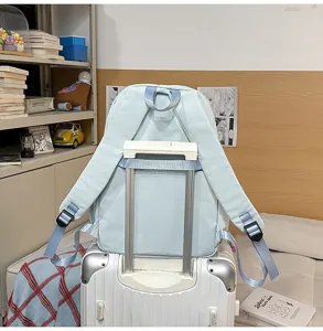 Light blue casual student school backpack with luggage strap, perfect for travel and daily use.