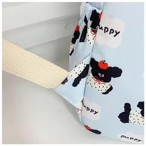 Close-up detail of light blue cute puppy cartoon print backpack with beige straps.