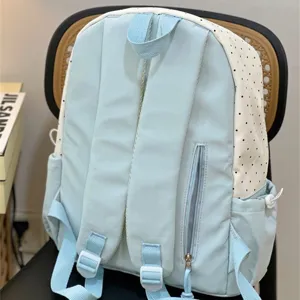 Vue détaillée du sac à dos décontracté bleu clair et blanc à pois avec bretelles.