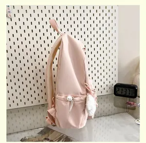 Pink casual student backpack with side pocket and cute fluffy plush pendant for daily school use.