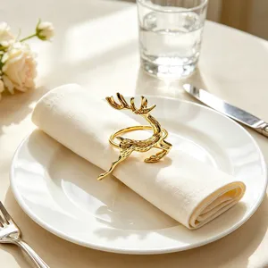 Close-up of a luxurious gold reindeer napkin ring on a white cloth napkin and ceramic plate.