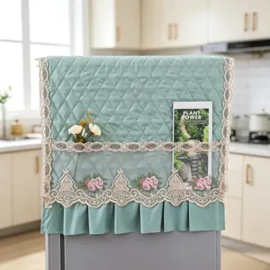 Housse anti-poussière matelassée pour réfrigérateur avec bordure en dentelle et poche brodée de fleurs.