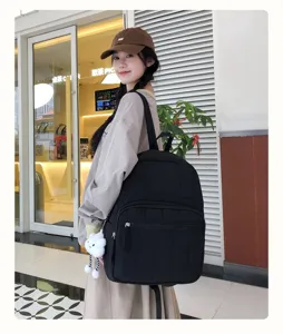 Detail view of the black quilted backpack with zipper pocket and cute cloud pendant on model.