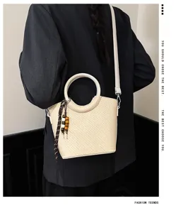 Sac seau tressé chic avec poignée ronde, bandoulière et charm en perles de bois pour femmes.