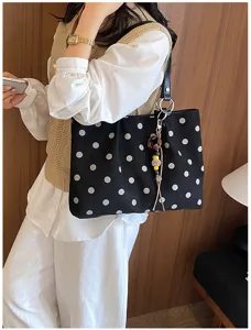 Detail shot of women's black polka dot suede tote shoulder bag, stylish commuter accessory.