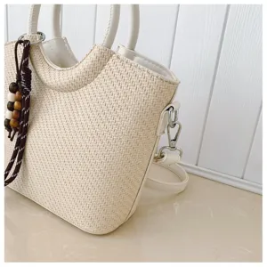 Gros plan d'un sac seau tressé beige chic avec des poignées en cuir et perles en bois.