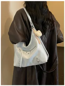 Trendy light blue leather shoulder bag with metal studs and cute bear charm pendant.