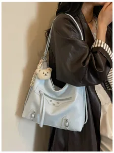 Detailed view of light blue leather hobo shoulder bag with metal studs and bear charm.
