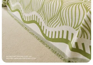 Dettaglio copridivano in tessuto verde retro, telo arredo strutturato con eleganti nappe per la casa.