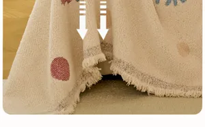 Close-up detail of soft fleece sofa blanket featuring cute polka dots and delicate fringe hem.