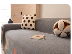 Detailed view of grey textured sofa blanket throw with decorative pillows in a modern living room.